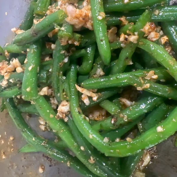 Close-up of vibrant green beans seasoned with garlic and spices, a soul-food side dish.