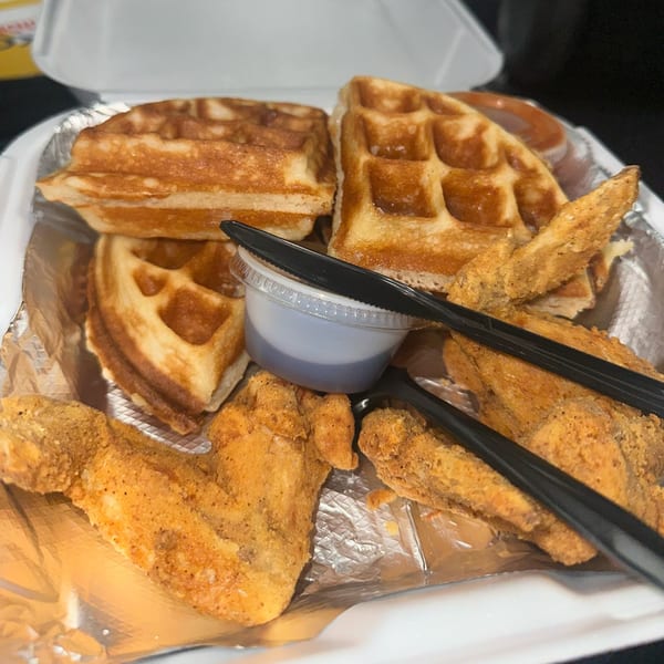 Soul food chicken and waffles with syrup in a to-go container from 1930 Classic Kitchen.